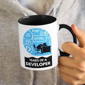 May include: White coffee mug with a black rim and handle. The mug features a blue circle with a black silhouette of a person slumped over a desk with a computer monitor. The circle is surrounded by various programming languages, including PHP, C#, HTML, JS, and SQL. The text "Tears of a Developer" is printed below the circle.