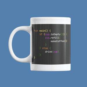 以下が含まれることがあります： 緑色のフォントでコードが表示された黒い画面が付いた白いセラミック製のマグカップ。コードは「fun main() { if (cup.isEmpty()) { cup.refill( makeCoffee() ) } else { drink(cup) } }」と表示されています。