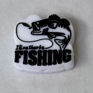 May include: A white, rectangular emblem with a black graphic of a fish and the words "I'd rather be FISHING." The fish is depicted with a hook in its mouth, and the text is in a bold, sans-serif font.