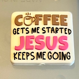 May include: White rectangular sign with the text "COFFEE GETS ME STARTED JESUS KEEPS ME GOING". The word "COFFEE" is in brown with a small coffee cup icon. The word "JESUS" is in pink.