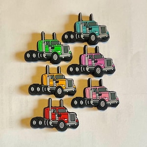 May include: Six toy semi-trucks in different colors: teal, green, pink, yellow, red, and orange. Each truck has a trailer and six wheels.