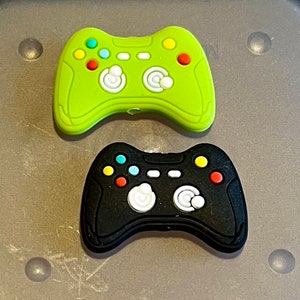 May include: Two plastic toy game controllers, one green and one black, with buttons and joysticks.