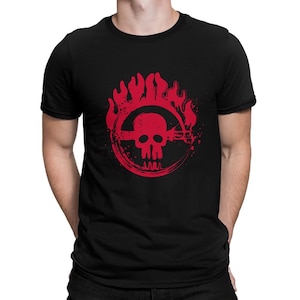 May include: Black t-shirt featuring a red skull graphic within a circular design with flames. The graphic includes a horizontal line through the skull and a jagged line below. The shirt is a crew neck style.
