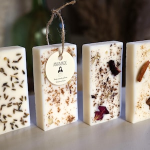 K&ouml;nnte beinhalten: Vier rechteckige wei&szlig;e Wachsschmelzen mit verschiedenen eingebetteten Botanicals. Die Wachsschmelzen sind in einer Reihe auf einer wei&szlig;en Oberfl&auml;che angeordnet. Die Wachsschmelze links hat Lavendelknospen, die n&auml;chste hat getrocknete Blumen und Kr&auml;uter, die dritte hat getrocknete Rosenbl&auml;tter und die letzte hat Zimtstangen und getrocknete Zitrusfr&uuml;chte.