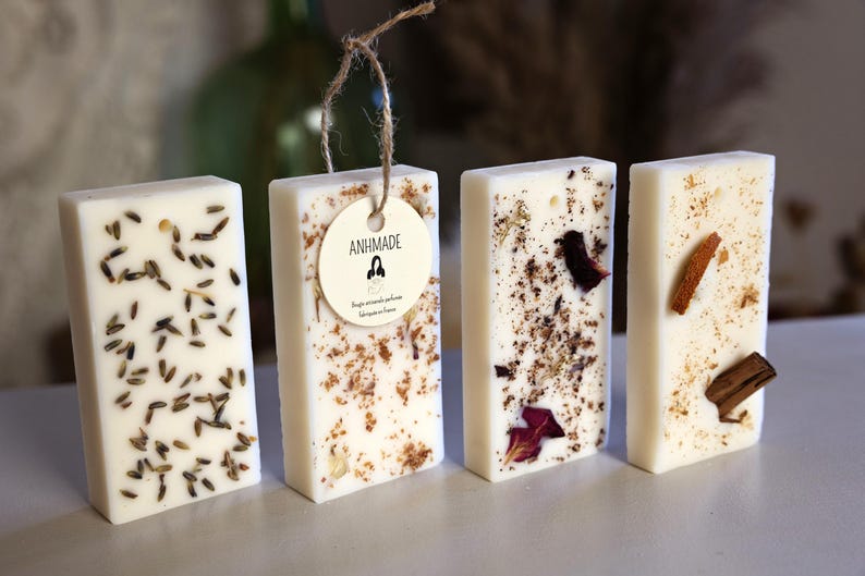 K&ouml;nnte beinhalten: Vier rechteckige wei&szlig;e Wachsschmelzen mit verschiedenen eingebetteten Botanicals. Die Wachsschmelzen sind in einer Reihe auf einer wei&szlig;en Oberfl&auml;che angeordnet. Die Wachsschmelze links hat Lavendelknospen, die n&auml;chste hat getrocknete Blumen und Kr&auml;uter, die dritte hat getrocknete Rosenbl&auml;tter und die letzte hat Zimtstangen und getrocknete Zitrusfr&uuml;chte.