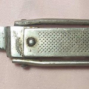 以下が含まれることがあります： 使い古された刃と穴あきハンドルが付いた、ヴィンテージのシルバー折りたたみナイフ。ハンドルには「98-011」の文字が刻まれています。ナイフは湾曲した刃と金属フレームで設計されています。