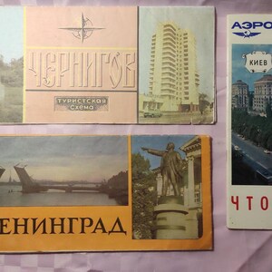 May include: A collection of vintage travel brochures and maps. The brochures feature images of buildings, bridges, and monuments, with text in Russian. One brochure is for Aeroflot Soviet airlines, with the city of Kyiv.