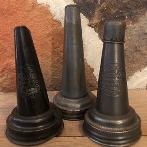 May include: Three vintage metal oil can spouts. The spouts are black and have a silver-colored rim. The spouts are labeled "The Nazro Mfg. Co.  Springfield, Ill.  U.S.A.  Accept No Substitute" and "The Nazro Mfg. Co.  Springfield, Ill.  U.S.A."