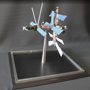 以下が含まれることがあります： 1986年から2001年まで軌道上にあったロシアの宇宙ステーション、ミール宇宙ステーションの模型です。この模型は金属とプラスチックでできており、銀色と灰色のカラーリングで塗装されています。模型は黒い台座に銀色のスタンドで取り付けられています。模型にはソーラーパネルとアンテナが付いています。模型には「MIR 1986-2001」とラベルが貼られています。