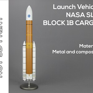 Op de afbeelding: Een model van de NASA Space Launch System (SLS) Block 1B Cargo raket. De raket is wit en oranje met het NASA-logo bovenop. De tekst "Launch Vehicle NASA SLS BLOCK 1B CARGO" is gedrukt op een grijze achtergrond. De tekst "Material: Metal and composite" is gedrukt onder de raket.
