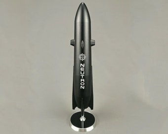 Pode incluir: Um modelo de foguete preto com a palavra "NEUTRON" impressa no lado. O foguete está em um suporte prateado com uma base preta.