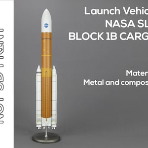 Op de afbeelding: Een model van de NASA Space Launch System (SLS) Block 1B Cargo raket. De raket is wit en oranje met het NASA-logo bovenop. De tekst "Launch Vehicle NASA SLS BLOCK 1B CARGO" is gedrukt op een grijze achtergrond. De tekst "Material: Metal and composite" is gedrukt onder de raket.