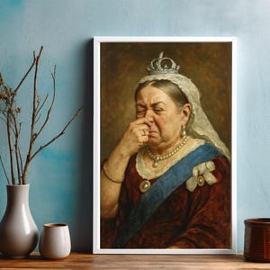 May include: Framed portrait of a woman in a crown and jewels, pinching her nose. The painting features a dark red dress, a blue sash, and a white lace veil. The artwork is displayed on a wooden surface.
