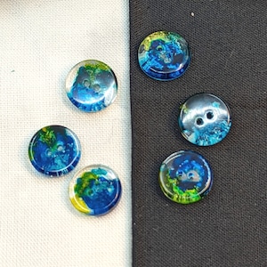 Op de afbeelding: Zes kleurrijke knopen met een blauwe, groene en gele swirl-ontwerp. De knopen zijn gemaakt van glas en hebben een glanzende afwerking.