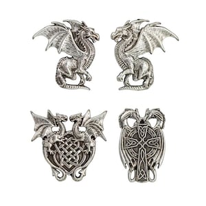 May include: A set of four silver-toned metal pins featuring dragon motifs. Two pins depict individual standing dragons with wings spread, one pin shows two dragons flanking a central Celtic knot, and one pin displays two dragons above a Celtic cross.