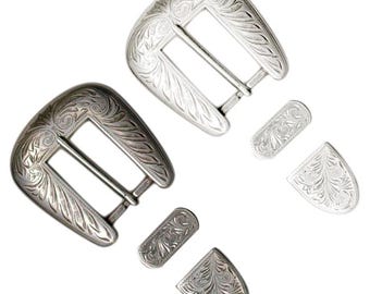 May include: Two silver-colored belt buckles with matching decorative pieces. The buckles and pieces have an engraved floral design. One buckle is a darker silver color than the other.