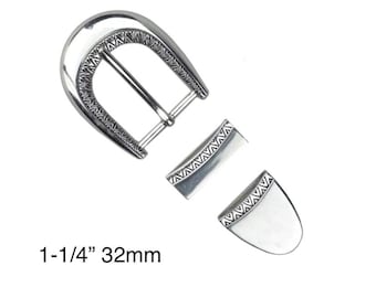 May include: Silver-toned belt buckle set with decorative geometric patterns. The set includes a buckle, a belt loop, and a tip. The text on the image reads "1-1/4" 32mm".