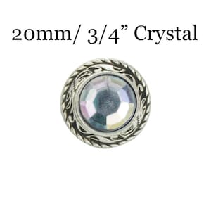 May include: A silver-toned metal button with a 3/4 inch crystal center. The button has a decorative design around the edge.