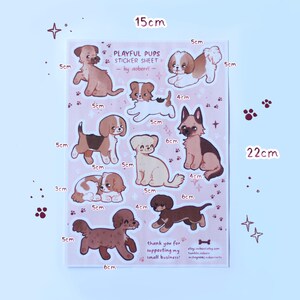 May include: A sticker sheet featuring nine playful puppy illustrations in various poses. The sheet is pink with white outlines and measures 15 cm by 22 cm. The text "Playful Pups Sticker Sheet" is at the top of the sheet, with the artist's name "by aoberri" below it.