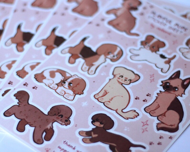 May include: A sheet of stickers featuring various dog breeds in a cartoon style. The stickers are on a pink background with white stars and paw prints. The text "So many pups, so little time" is at the top of the sheet.