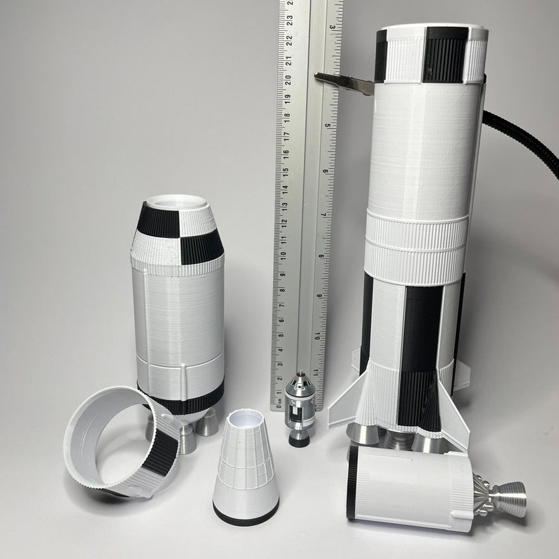 K&ouml;nnte beinhalten: Ein Satz von drei wei&szlig;en und schwarzen 3D-gedruckten Modellraketen. Die Raketen sind unterschiedlich gro&szlig; und haben verschiedene Details, darunter Fl&uuml;gel, Triebwerke und eine Nasenspitze.