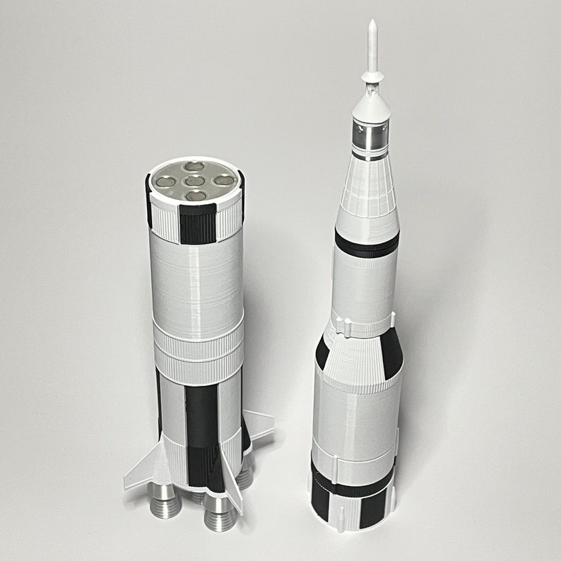 K&ouml;nnte beinhalten: Zwei wei&szlig;e und schwarze Modellraketen, eine mit einer spitzen Nasenspitze und die andere mit einer runden Nasenspitze. Beide Raketen haben ein schwarz-wei&szlig; gestreiftes Design.