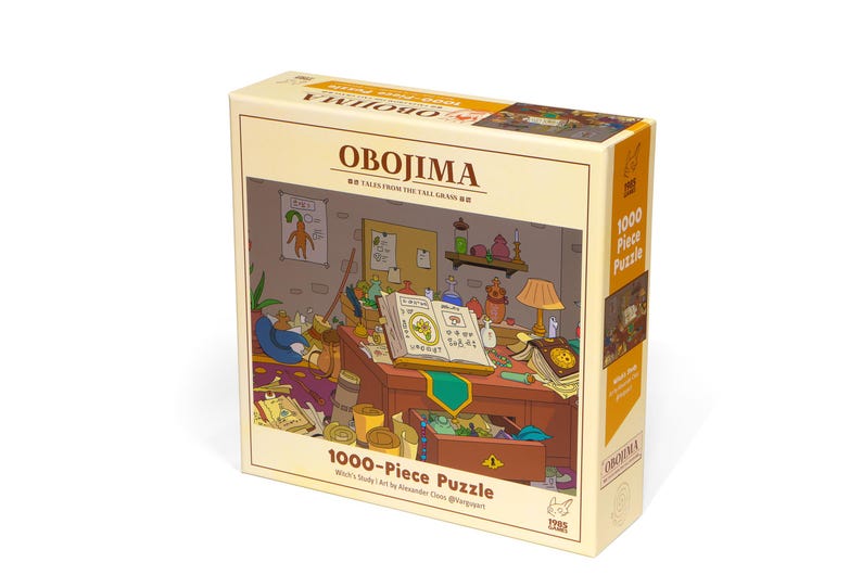 May include: A 1000-piece puzzle box with the title "OBOJIMA" and the subtitle "Tales from the Tall Grass." The box features an illustration of a cluttered desk with books, a lamp, and a whimsical cartoon scene. The box is beige and yellow.