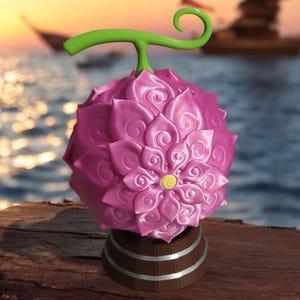 May include: A pink, flower-shaped object with a green stem and a yellow centre, resting on a brown base with silver bands. The background features a sunset over the ocean with a boat.