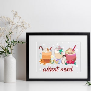 May include: A framed print with a white background and a winter-themed illustration of three mugs of hot beverages with whipped cream and toppings. The text "current mood" is written in red below the mugs.