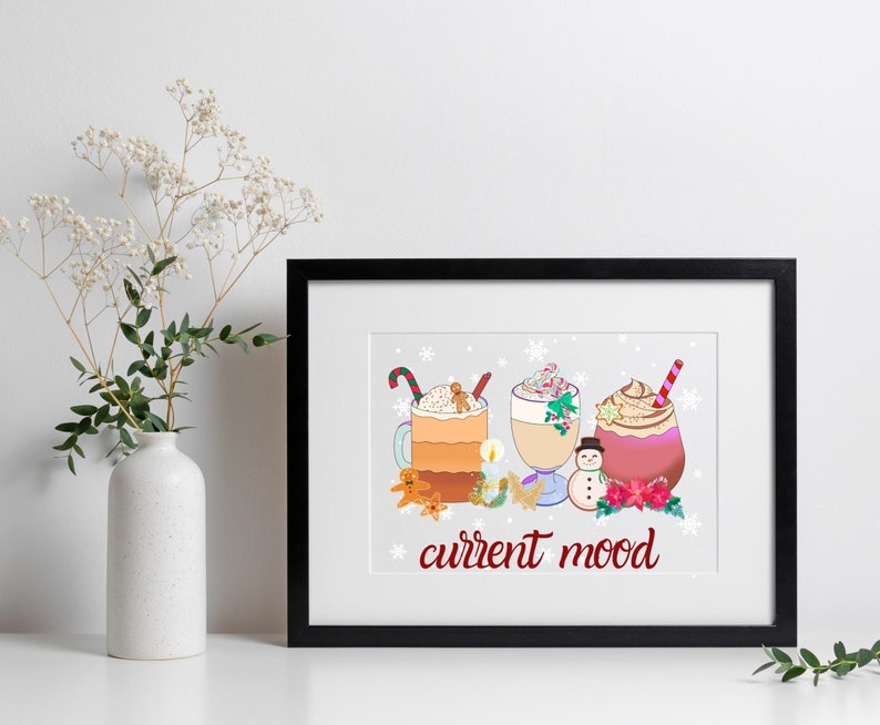 May include: A framed print with a white background and a winter-themed illustration of three mugs of hot beverages with whipped cream and toppings. The text "current mood" is written in red below the mugs.