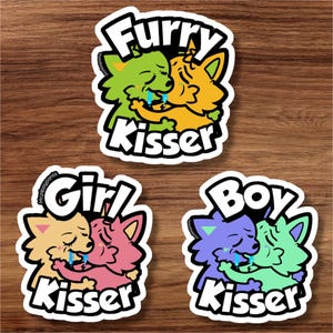以下が含まれることがあります： 3つのステッカー。毛むくじゃらのキャラクターがキスをしている漫画の画像です。上のステッカーには、緑と黄色のキャラクターで「Furry Kisser」と書かれています。下のステッカーには、ピンク、紫、緑のキャラクターで「Girl Kisser」と「Boy Kisser」と書かれています。