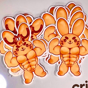 May include: A stack of stickers featuring a cartoon bunny and a cartoon reindeer with muscular bodies. Both characters are brown and have a light brown outline. The stickers are on a white background.