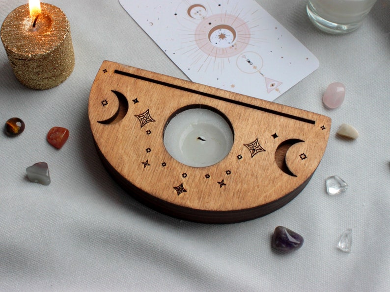 May include: A wooden crescent moon candle holder with two candle wells and a decorative design of moons and stars. The holder is made of light brown wood and has a natural finish.