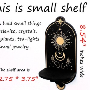 May include: A small black wooden shelf with a sun and moon design. The shelf is 8.54 inches wide and the shelf area is 2.75 by 3.75 inches.  The shelf is perfect for displaying small items like crystals, air plants, or jewelry.