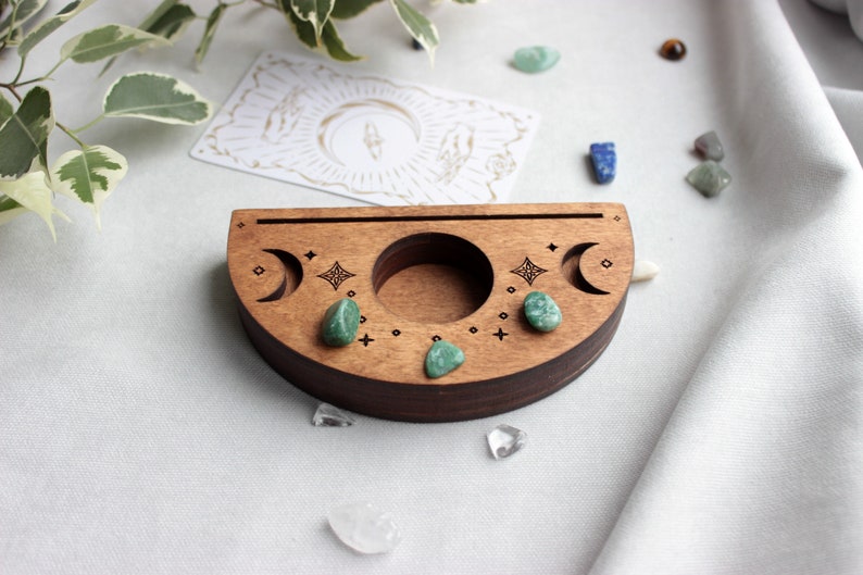 May include: A wooden crescent moon shaped tray with three small green stones and a carved design of moons and stars.