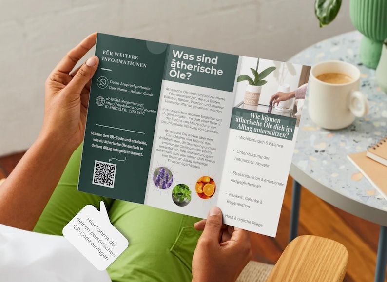 May include: A person holding a brochure with text in German about essential oils. The brochure is open, displaying information and images of lavender, mint, and oranges. A QR code is visible. A cup of coffee and a small plant are in the background.