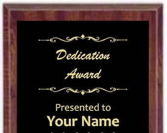 May include: A black plaque with a gold frame and gold lettering. The plaque reads "Dedication Award" and "Presented to Your Name". It also says "No Charge for Engraving" and "2022".