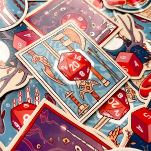 Pu&ograve; includere: Un set di adesivi colorati con dadi che mostrano numeri diversi. I dadi sono rossi e bianchi con numeri neri. Gli adesivi sono su uno sfondo blu con varie illustrazioni di spade, asce e altre immagini a tema fantasy.