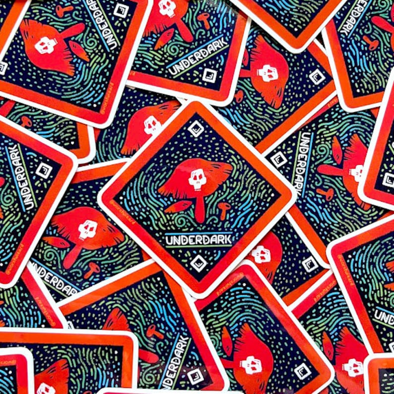 May include: A stack of square stickers with a black background and a red border. The stickers feature a mushroom with a skull on top, surrounded by a swirling pattern of green, blue, and white lines. The text "UNDERDARK" is printed in white on the stickers.