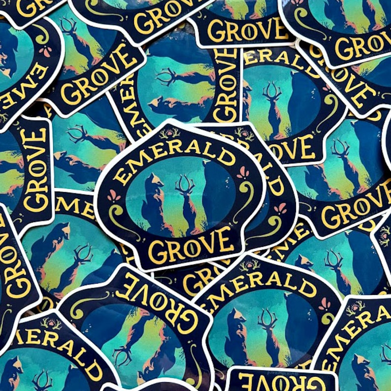 May include: A close-up of several stickers featuring a blue and yellow design with the text "Emerald Grove". The design features a fox and a deer standing in a forest setting.