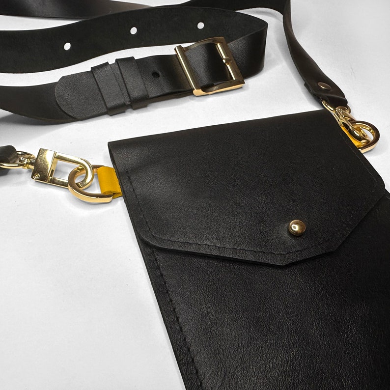 May include: A black leather crossbody bag with a gold chain and a flap closure. The bag has a small pocket on the front.