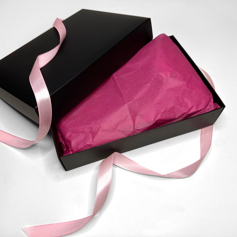 May include: A black gift box with a pink tissue paper lining and a pink satin ribbon.