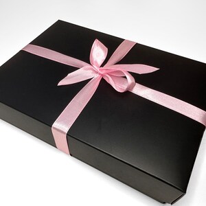May include: A black gift box with a pink satin ribbon tied in a bow.