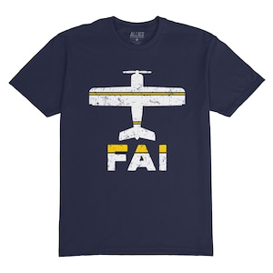 Peut inclure: T-shirt bleu marine avec une silhouette blanche d'un petit avion avec des accents jaunes et le mot "FAI" en dessous.