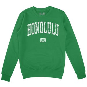 Op de afbeelding: Groen sweatshirt met een witte vintage-stijl grafische afbeelding met de tekst "HONOLULU" met "888" eronder.