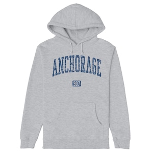 May include: A grey hooded sweatshirt with the word "ANCHORAGE" in blue lettering and the number "907" in a blue box below it.