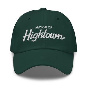 May include: A dark green baseball cap with white embroidered text that reads "MAYOR OF Hightown".
