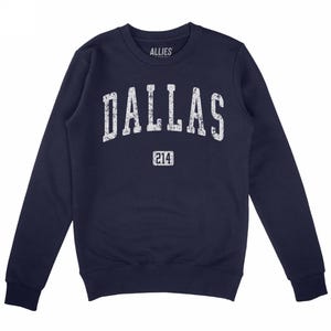 Puede incluir: Sudadera azul marino con la palabra "DALLAS" en letras blancas desgastadas en el pecho. Debajo, el número "214" en un rectángulo. La marca "ALLIES" está impresa encima.