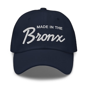 Puede incluir: Una gorra de béisbol azul marino con texto bordado en blanco que dice "Made in the Bronx".