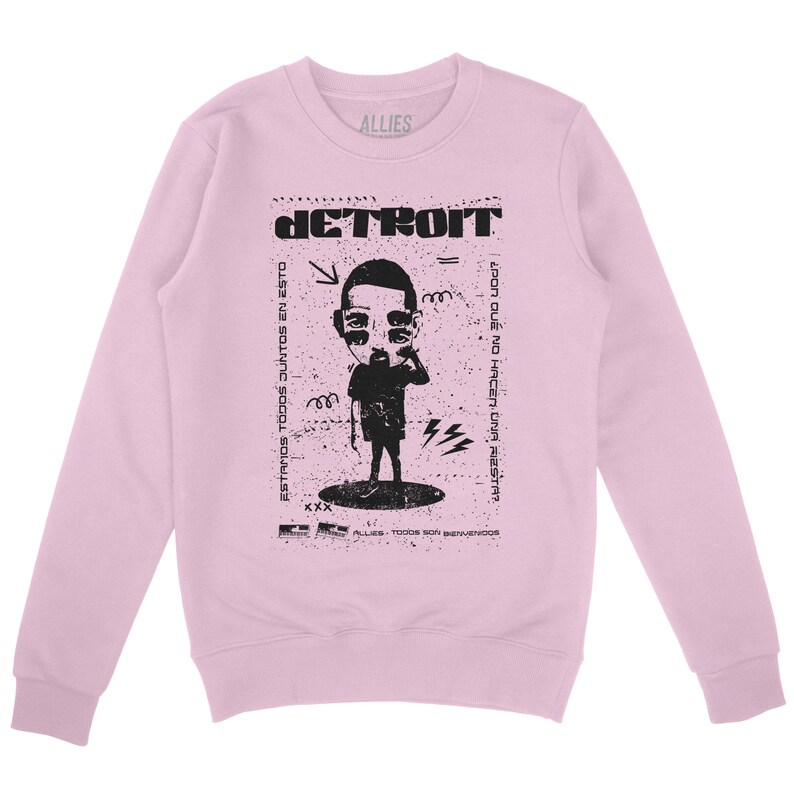 Peut inclure: Sweat-shirt rose &agrave; manches longues avec un imprim&eacute; graphique noir d'un personnage de dessin anim&eacute; avec le texte "DETROIT" et "ESTAMOS TODOS JUNTOS EN ESTO" et "&iquest;POR QUE NO HACEN UNA FIESTA?"